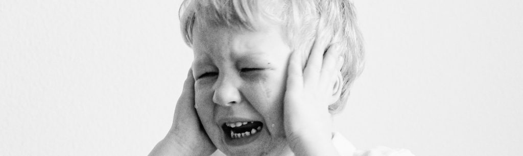 black-and-white-photo-of-a-boy-crying-and-holding-his hands over his ears sensory