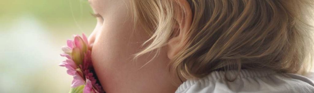 picture of a child smelling a flower