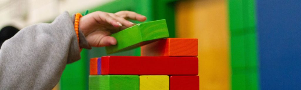 child building a tower with colourful, large bricks