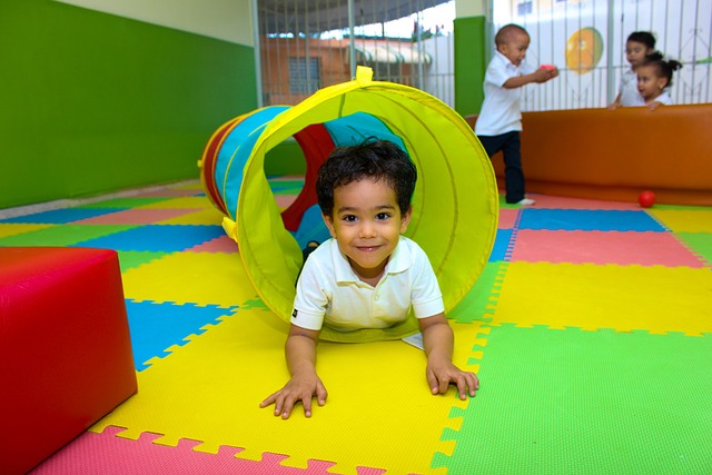 young boy crawling through a colourful tunnel. when should a child see an occupational therapist?